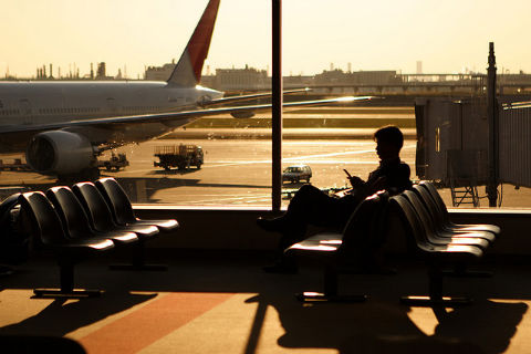 alternatives to working at your desk: a man sitting in an airport terminal near a window, used in blog 10 unique alternatives to working at your desk