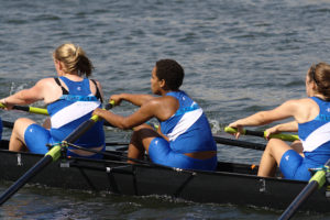 Three team members rowing in a boat, used for blog 4 lessons rowing can teach us about productivity management