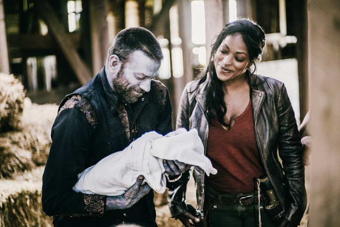Z Nation zombie holds a baby while a woman looks in happiness, used in blog The zombie apocalypse guide to remote working